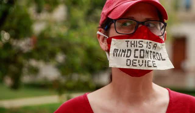 Woman wearing mask with the message "This is a mind contol device'.