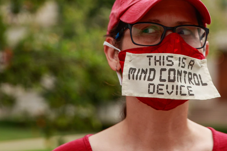 Woman wearing mask with the message "This is a mind contol device'.