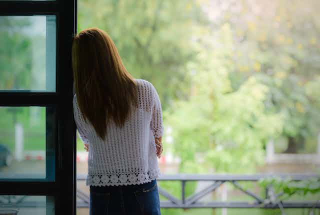 A woman looks out a window.
