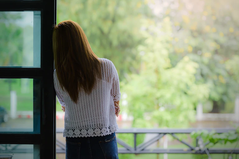 A woman looks out a window.