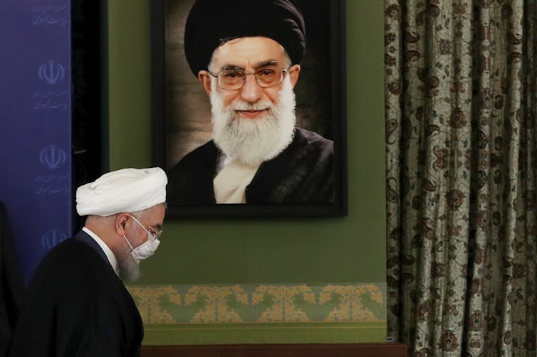 Iranian President Hassan Rouhani walking in front of a portrait of Supreme Leader Ayatollah Ali Khamenei