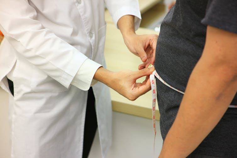 Doctor measures person's stomach.