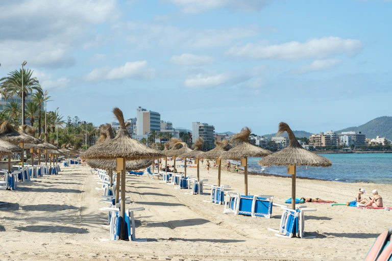 playa vacía con sombrillas y sillas apiladas.