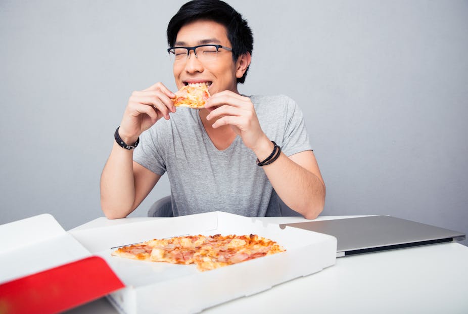 Young Asian man eating pizza