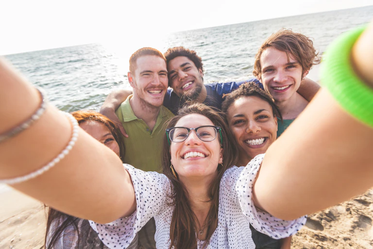 un grupo de chicas y chicos se hacen una foto en la playa