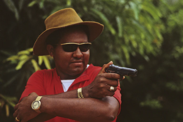 Man in hate with a gun and flashy jewelry