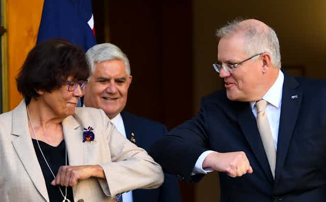 Indigenous leader Pat Turner elbow bumping Prime Minister Scott Morrison, as Minister for Indigenous Affairs Ken Wyatt looks on, smiling