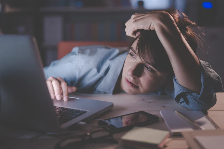 Person working on a laptop at messy desk at home