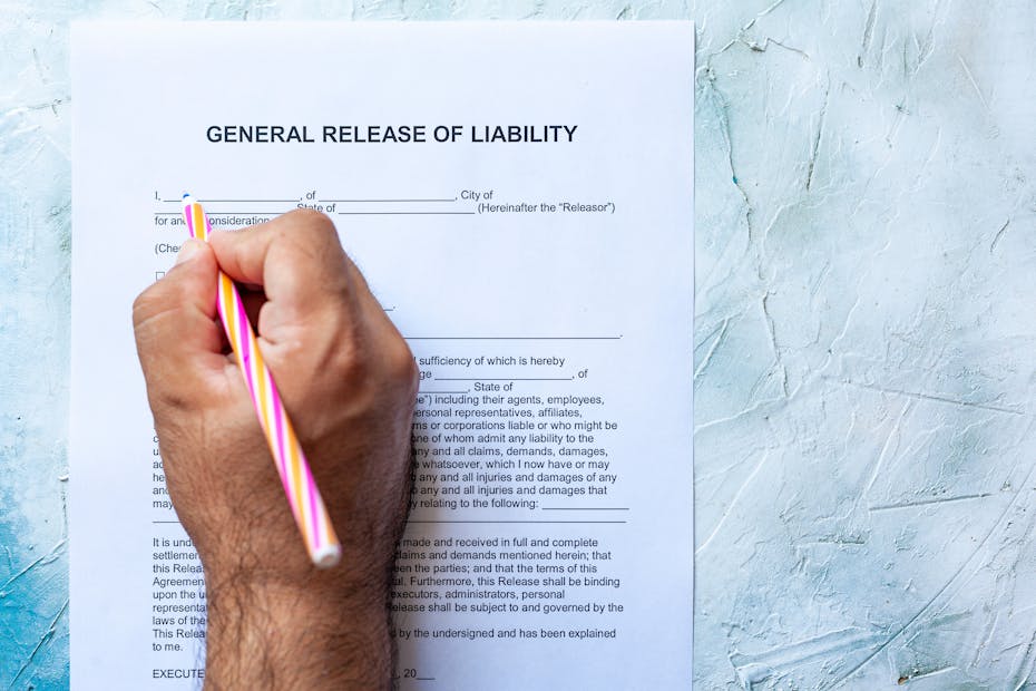 A man's hand grasps a pink pencil and prepares to sign a liability waiver.