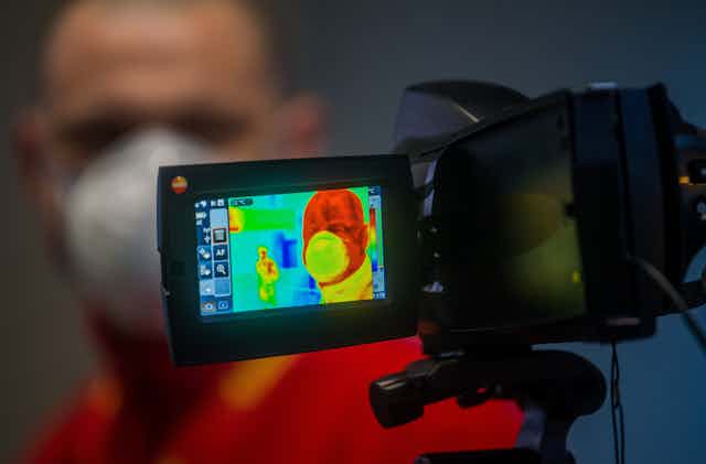 A man has his temperature taken with an infrared thermal camera. 