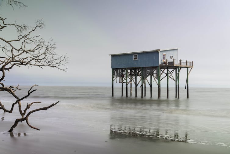 A cabin raised several feet above the sea water on stilts.