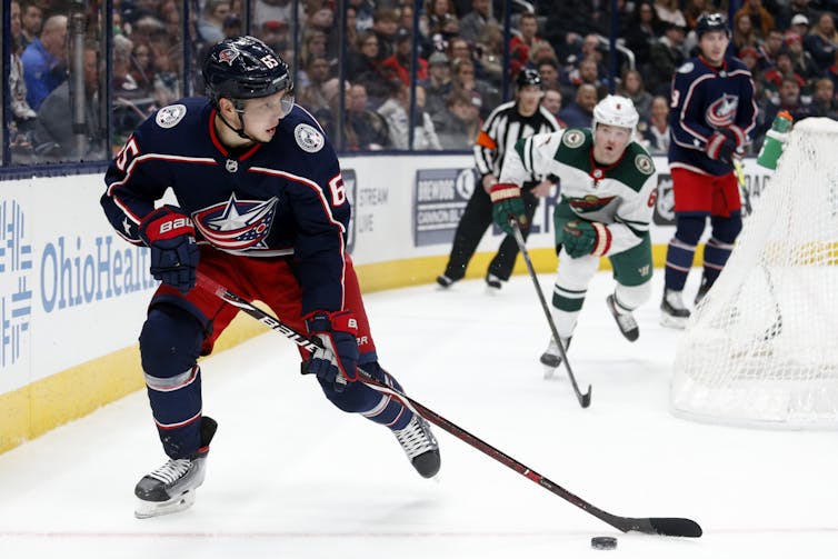 A hockey player controls the puck behind his own net.