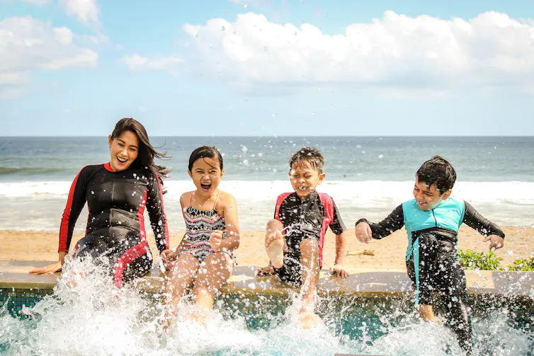 Family splashing in water by the seaside.