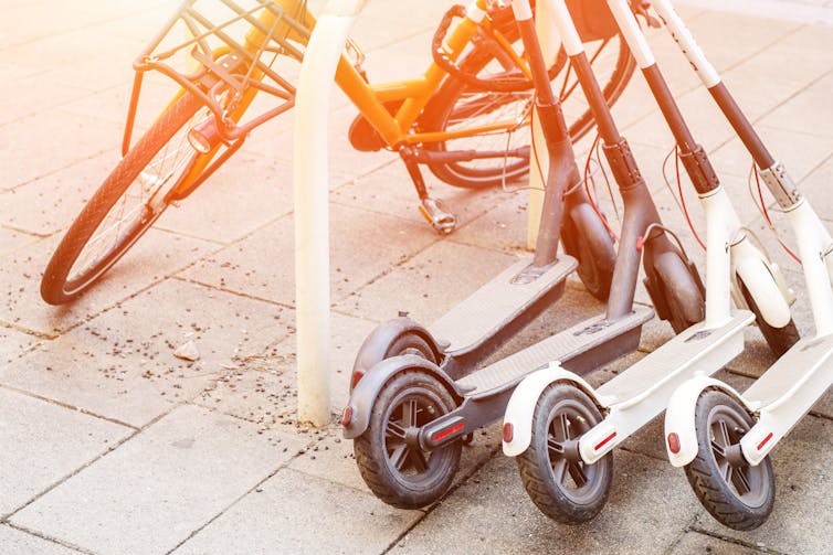 A bike and three electric scooters on the street