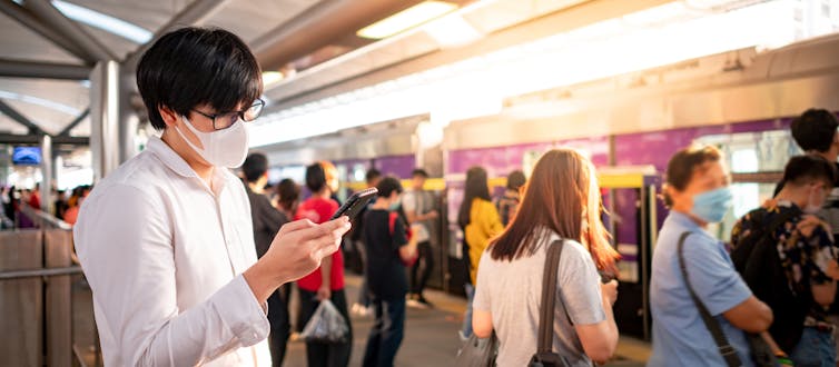 Grupo numeroso de personas con mascarillas esperando en el andén de una estación de metro