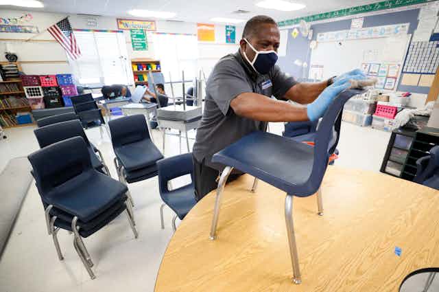 A school employee wipes down a chair