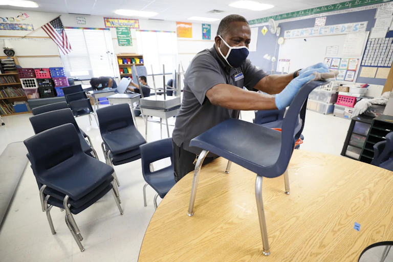 A school employee wipes down a chair
