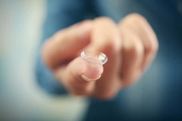 Finger with contact lens balanced on fingertip