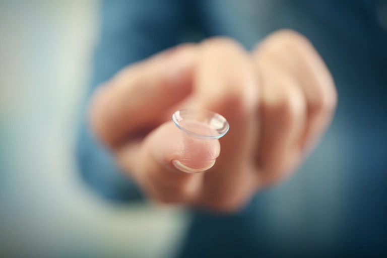 Finger with contact lens balanced on fingertip