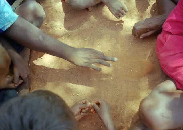 Hands of Indigenous Australians sitting in circle