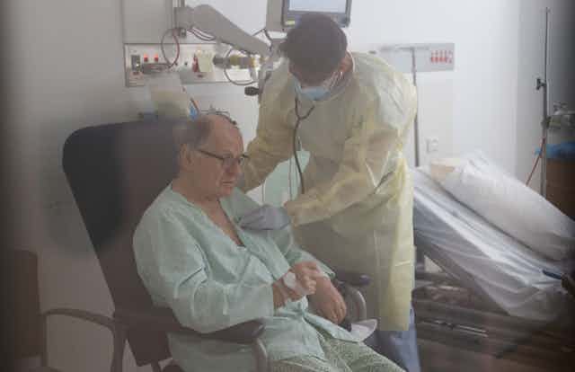 Elderly man being tended to by a hospital doctor