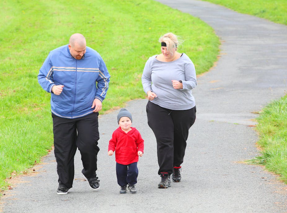 Overweight parents jog with their toddler.