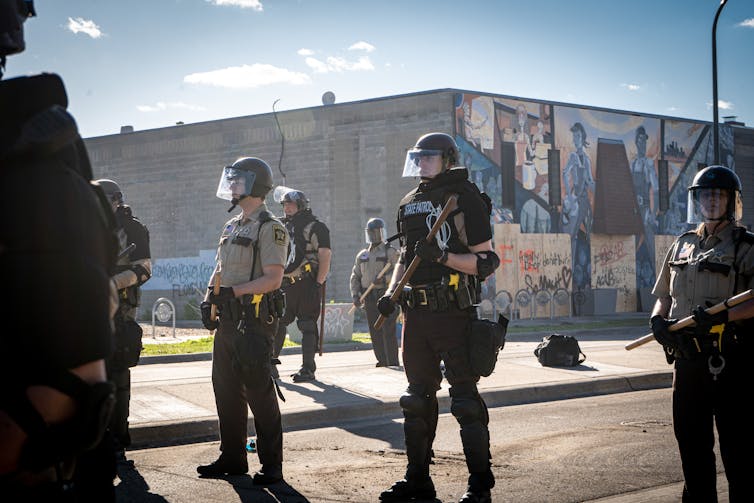 Armed police in riot gear stand in formation