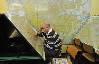 Uomo che studia enormi mappe di Londra