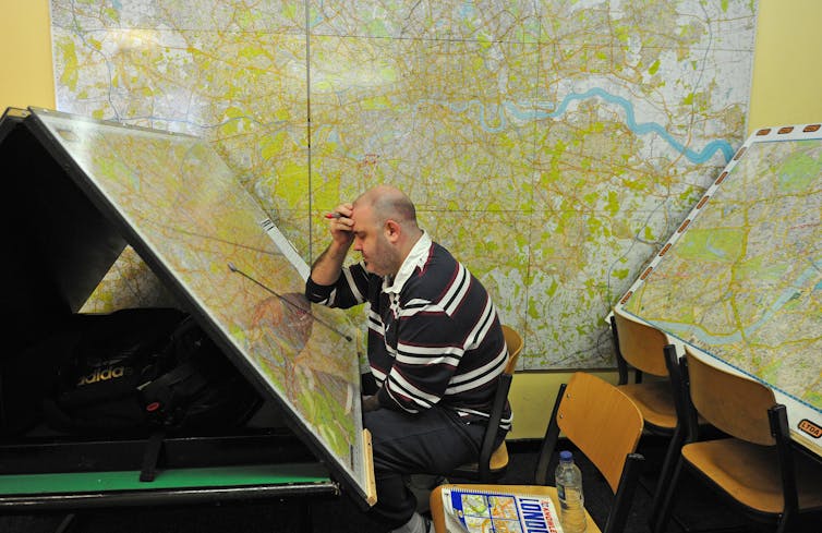 Homem estudando mapas enormes de Londres