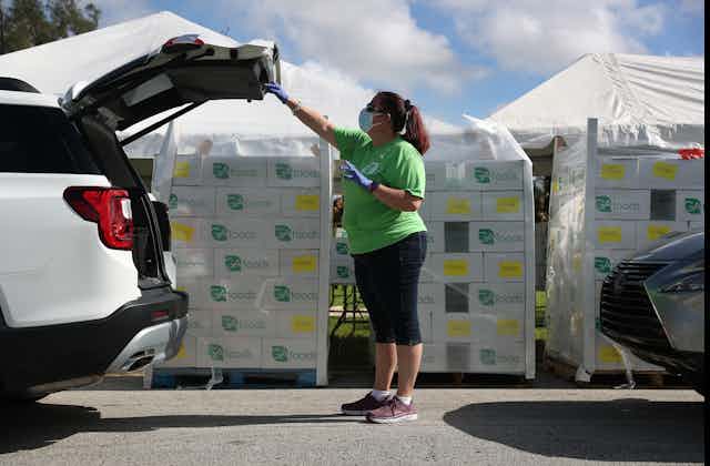Loren Mennes place food in the back of a vehicle at a drive-thru food distribution site set up at the First Church of the Brethren on July 24 in Miami, Florida.