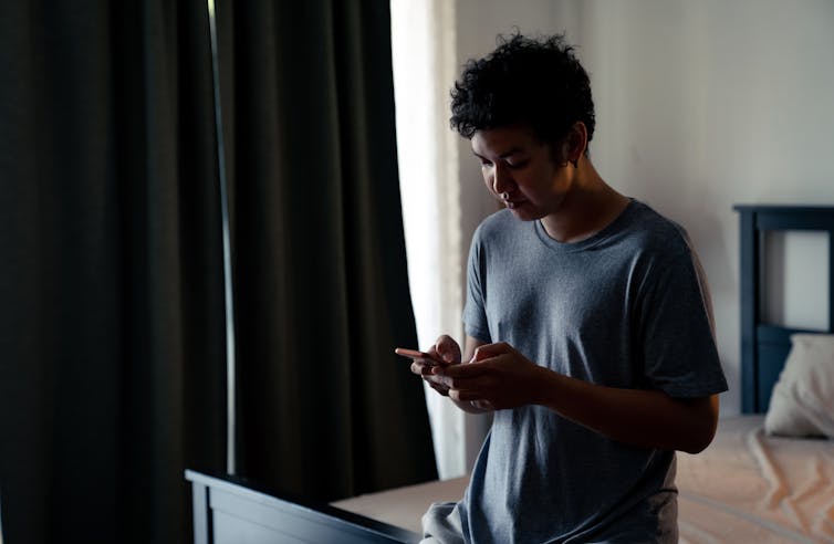 Man looking at phone in bedroom