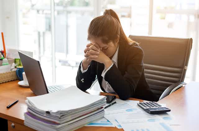Woman resting her head in her hands at her desk.