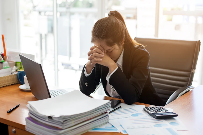 Woman resting her head in her hands at her desk.