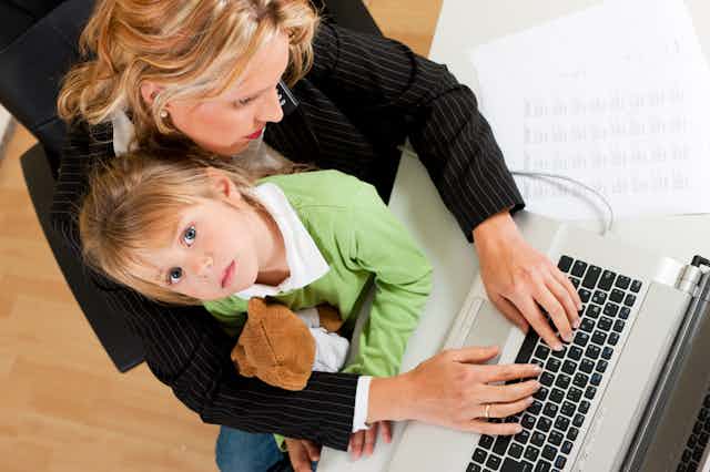 Woman using laptop computer with child sitting on her lap.