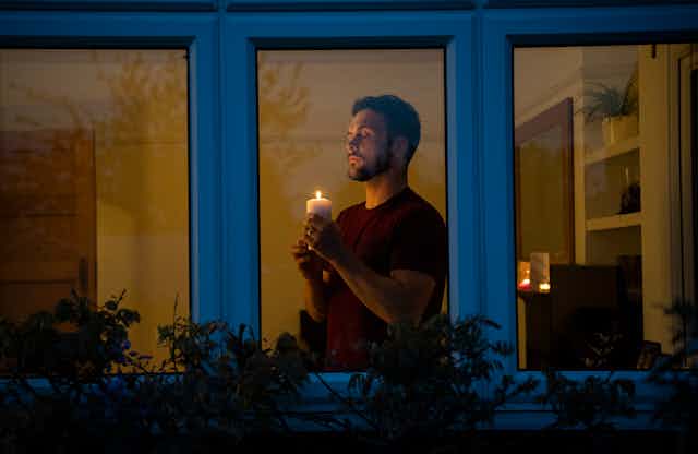 A man holds a candle at home in lockdown.