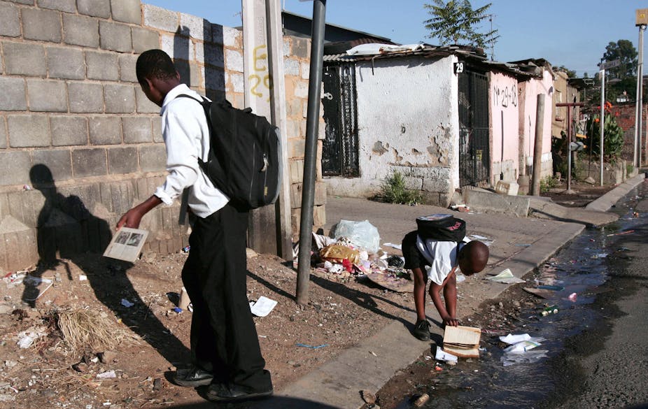 Schoolboys on the street, where a blocked drain is causing dirty water to leak out