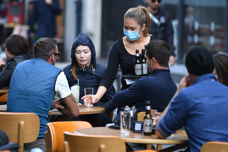 Woman serves drinks at bar in London.