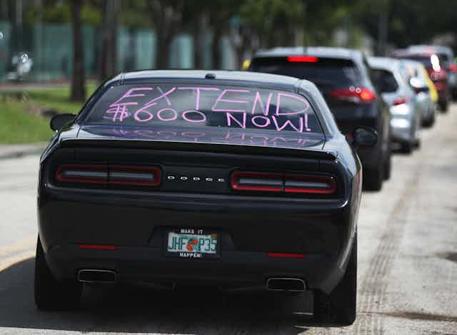 A car with 'extend $600 now!' written on its rear window participates in a caravan protest on July 16 in Miami Springs, Florida. 