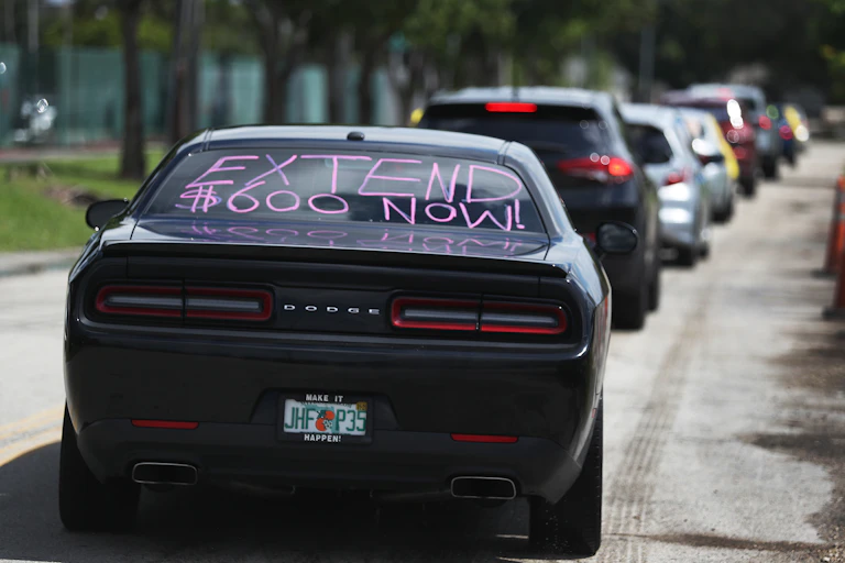 A car with 'extend $600 now!' written on its rear window participates in a caravan protest on July 16 in Miami Springs, Florida.