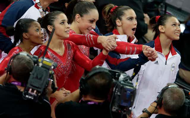Five young gymnasts look up nervous and excited.