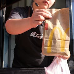 McDonald's worker hands over order at a drive-through counter.