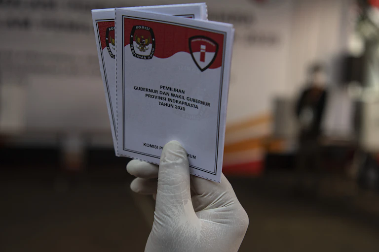 Seseorang menunjukkan contoh surat suara untuk Pilkada