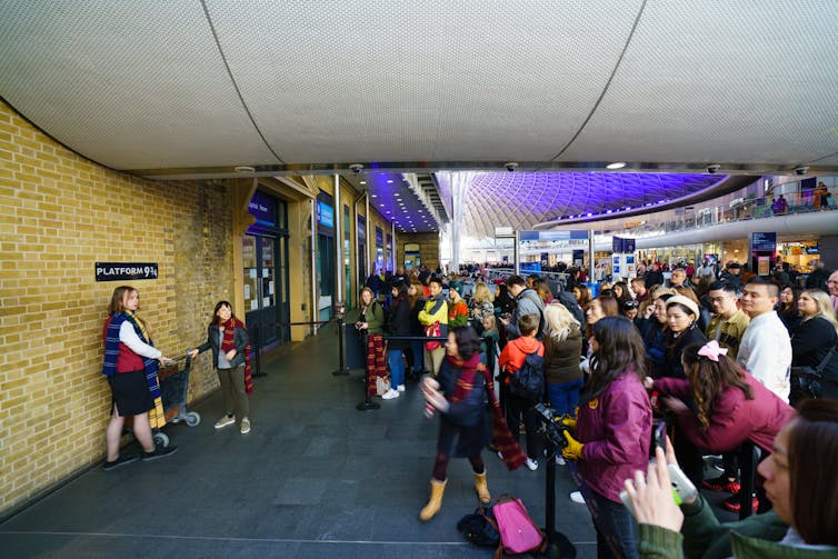 Fans wait for a photo opportunity at the Harry Potter platform 9 3/4 at King's Cross Station, London