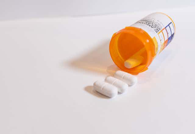 Antibiotic pills spilling out of a bottle.