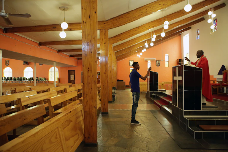 Parishionr holds up mobile phone to record priest conducting mass in an empty church