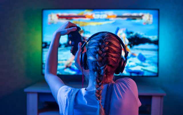 Una joven juega a videojuegos en una pantalla de televisión.