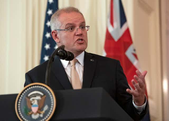 Scott Morrison delivers a speech in front of an American and Australian flag