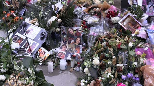 A memorial comprising photos of victims, flowers and candles on a pavement.
