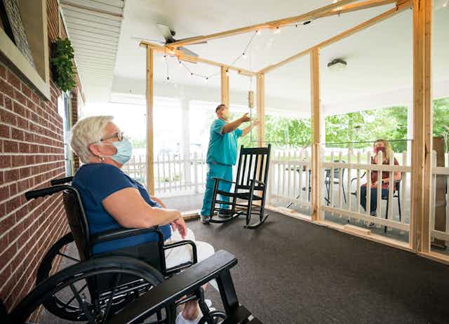 Maintaining social distance, a resident at a Midwest nursing home talks with a visitor.