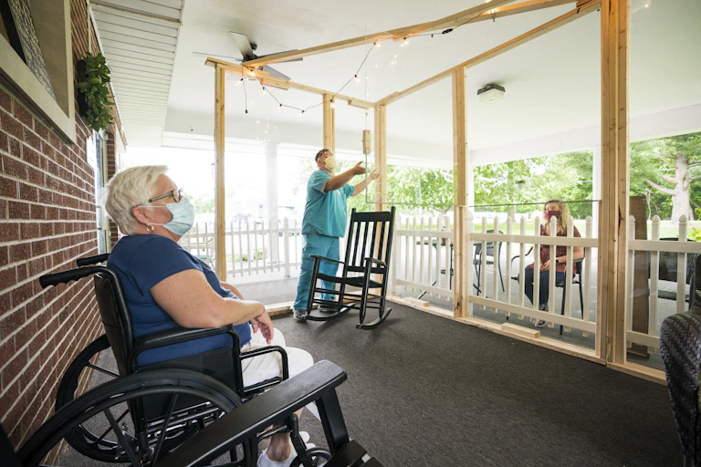 Maintaining social distance, a resident at a Midwest nursing home talks with a visitor.